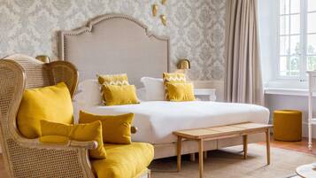 Een slaapkamer met een bed, een stoel, een nachtkastje, een lamp en een raam.