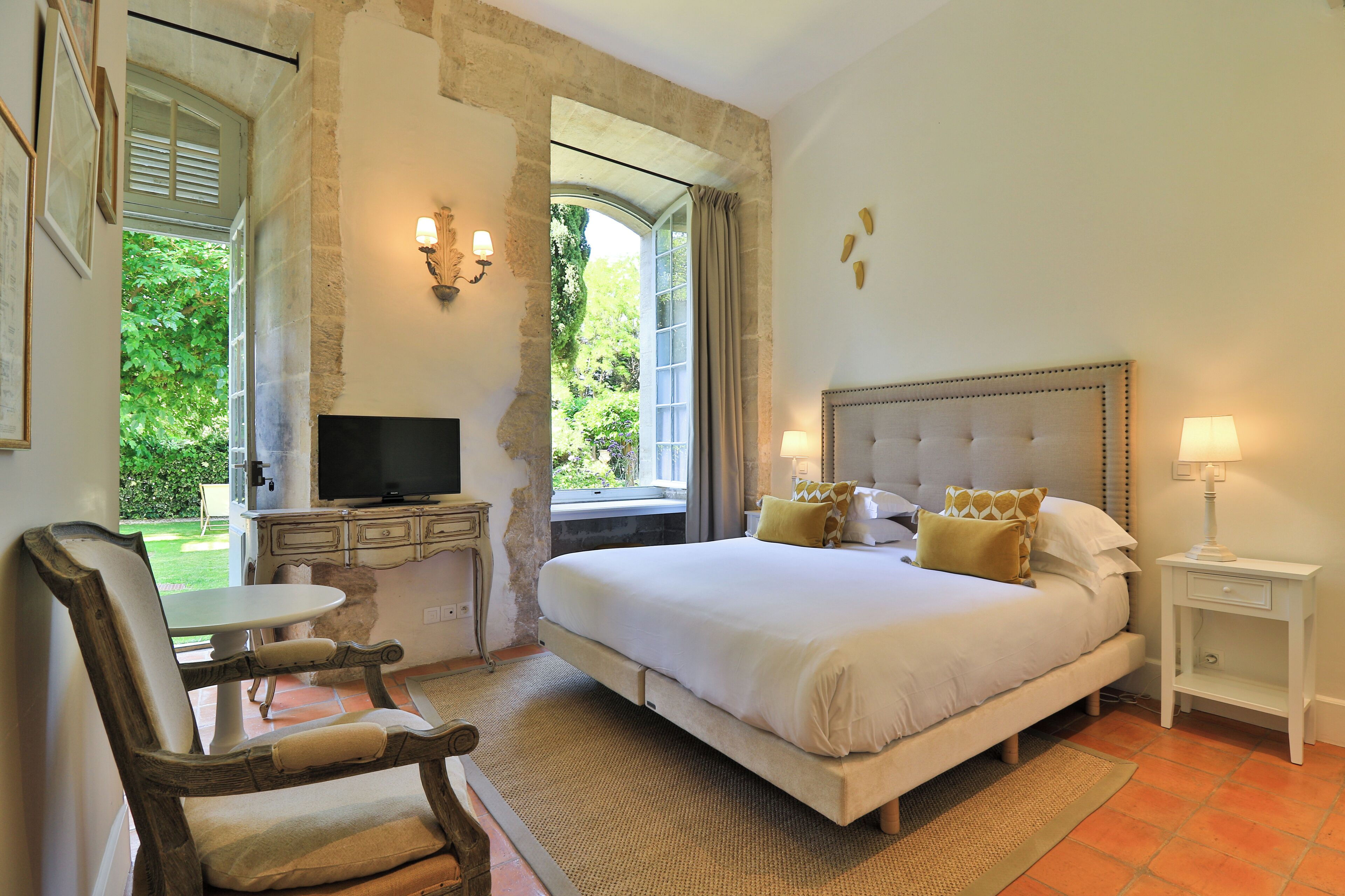 A bedroom with a bed, a television, a chair, and a small table.