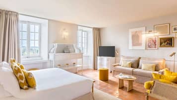 A hotel room with a bed, a sofa, a TV, a desk, and a window.