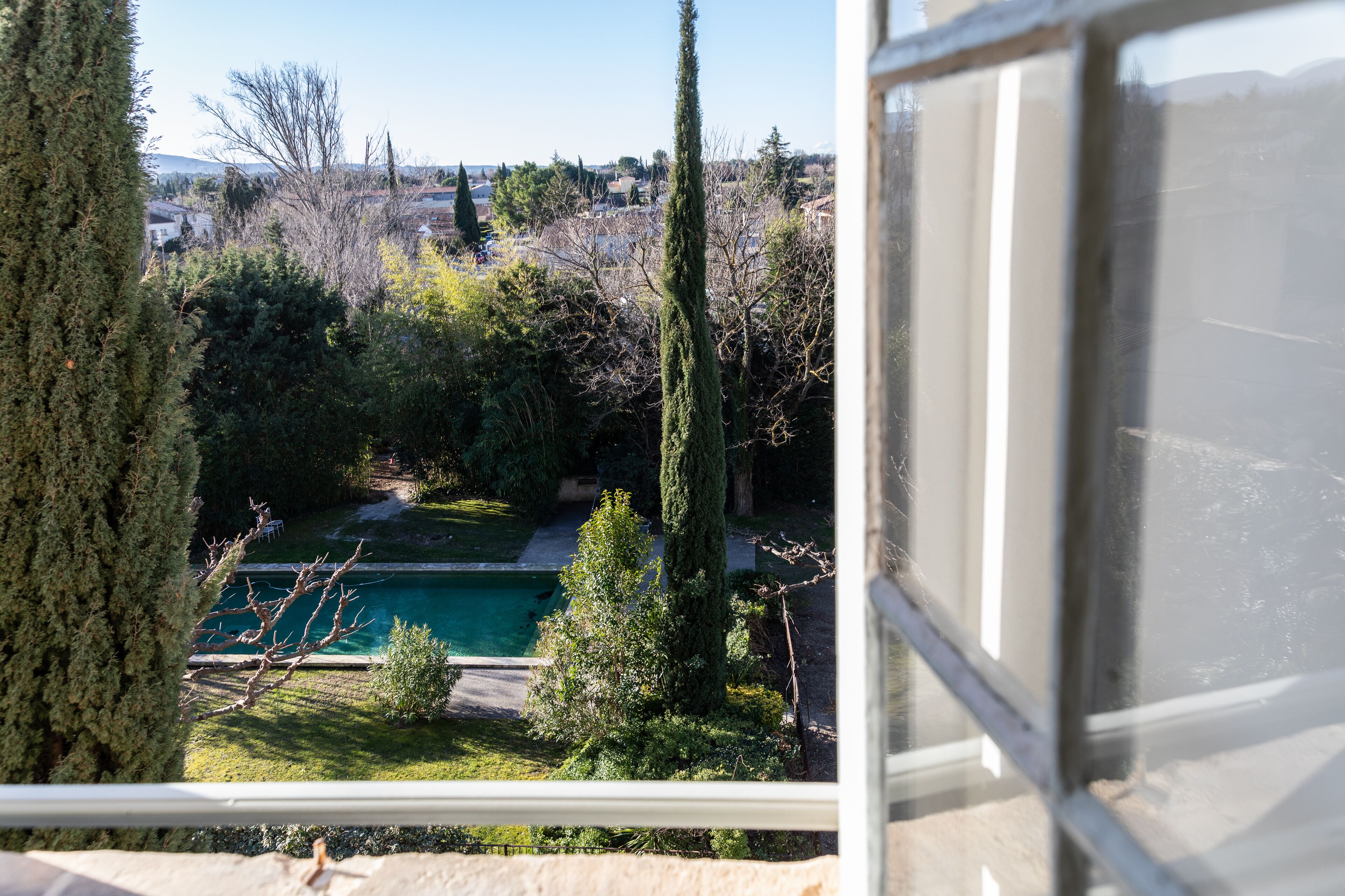 Vista de una piscina rodeada de árboles y un pueblo a lo lejos.