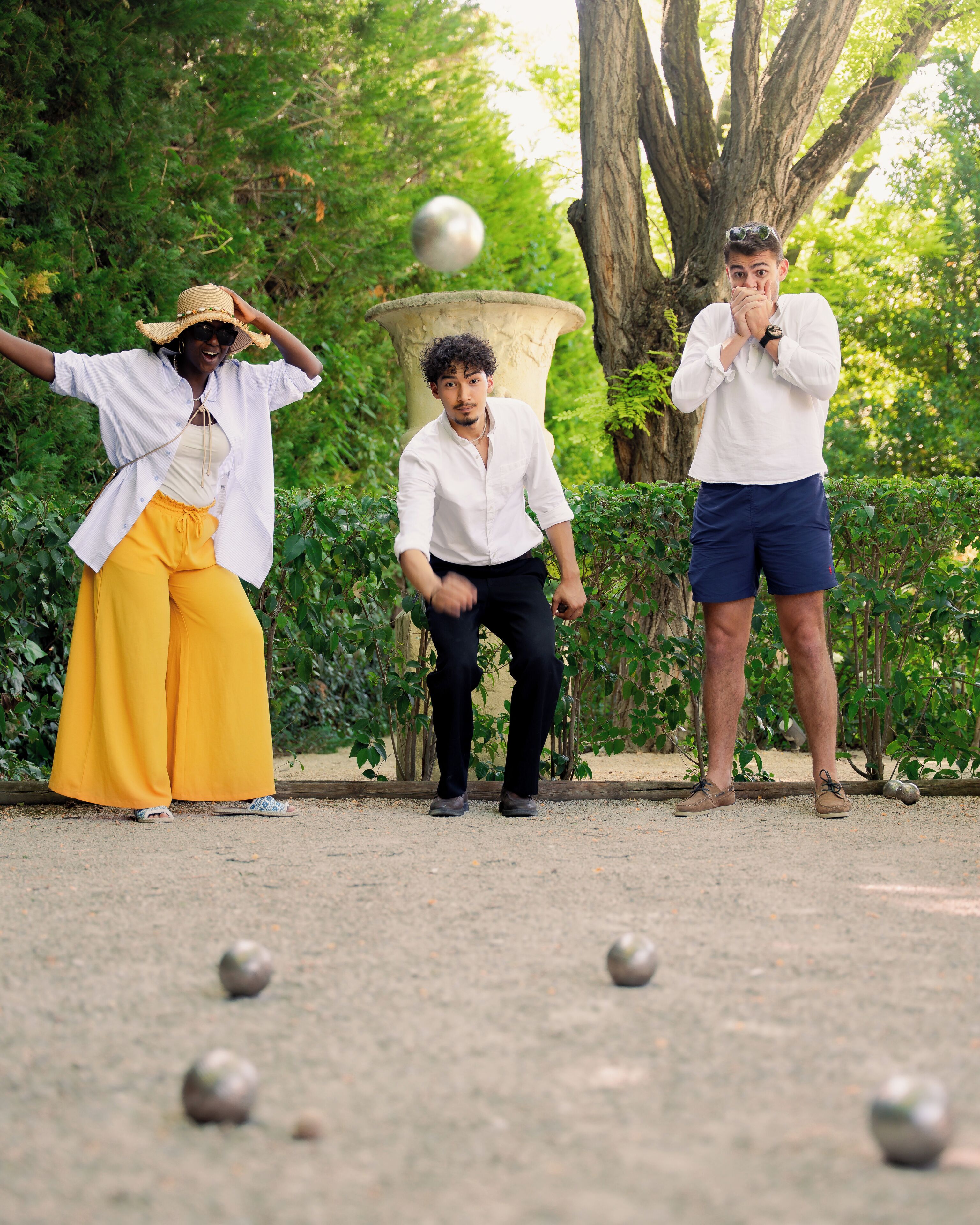 Una persona con camisa blanca y pantalones amarillos jugando a un juego con pelotas y una piedra.