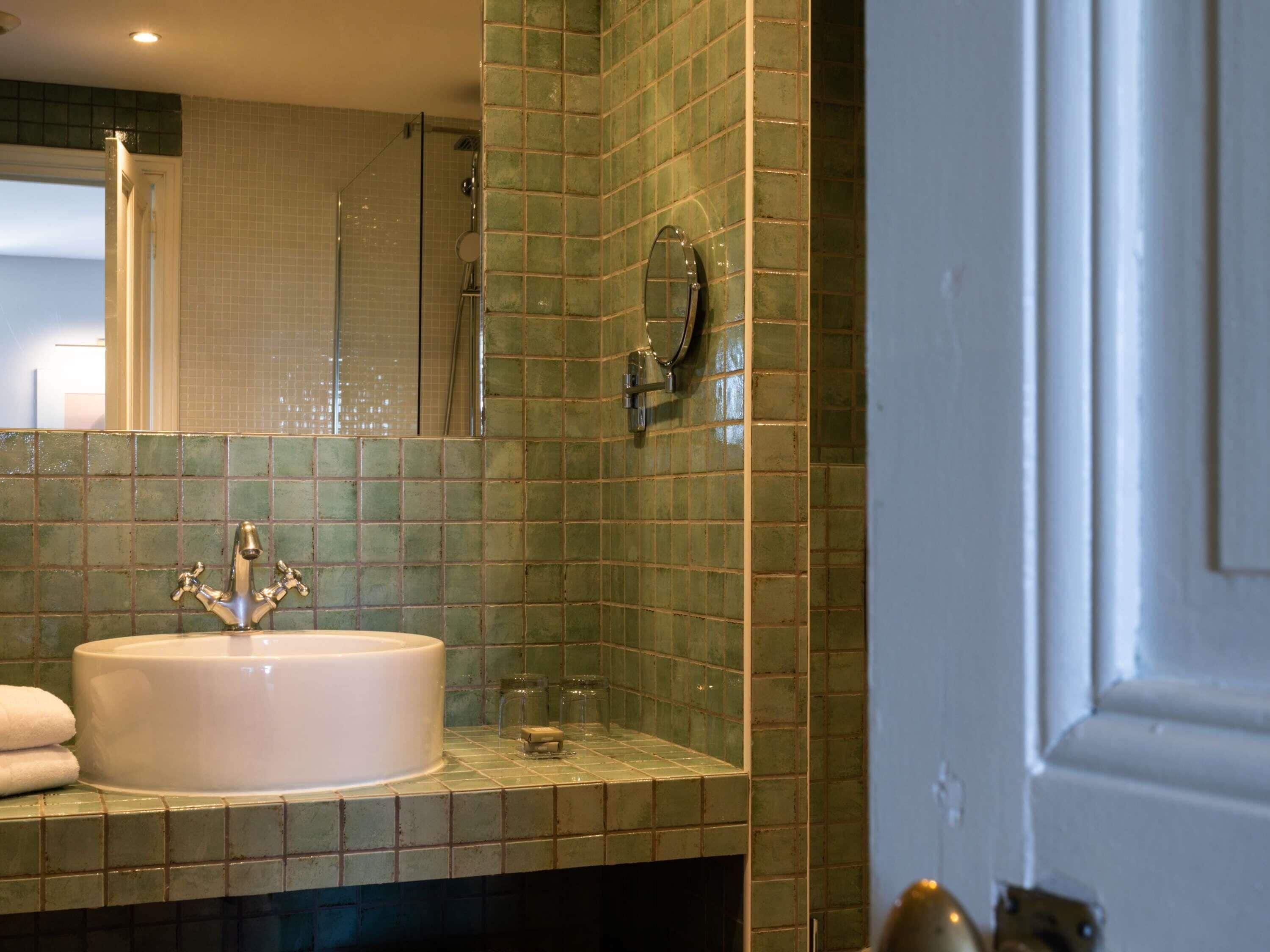 A bathroom with a sink, mirror, and shower.