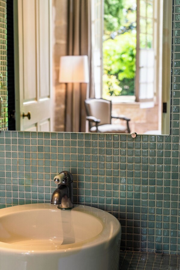 A bathroom with a sink, mirror, and green mosaic tiles. - Chateau de Mazan - Handwritten Collection (Mazan)