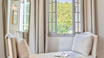 Een kamer met een raam, een spiegel, een bank en een paar brillen op de bank.
