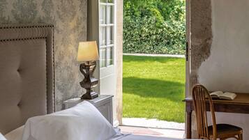 Une chambre à coucher avec un lit, une table de chevet avec une lampe, une chaise et une vue sur un jardin.