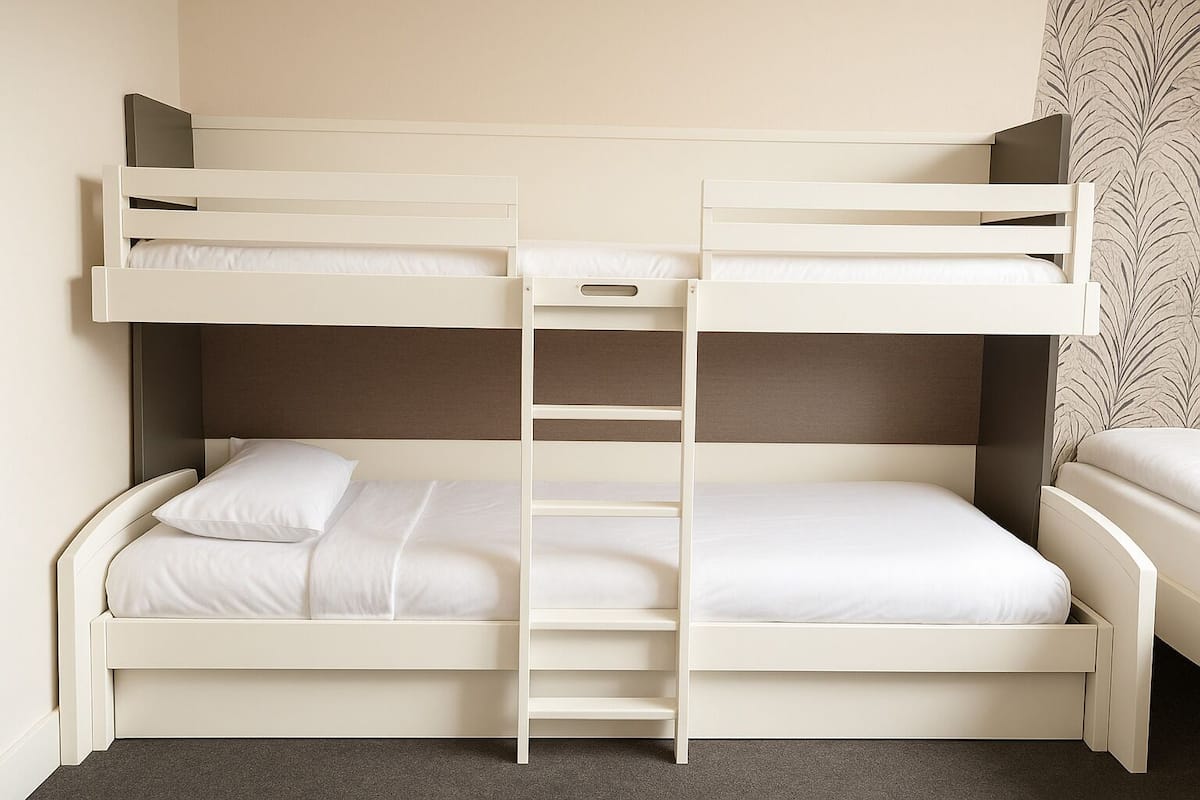 Una cama litera con escalera, ropa de cama blanca y una alfombra gris.