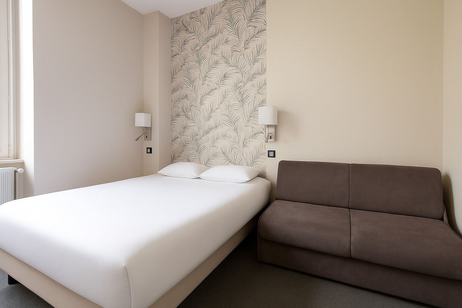 A hotel room with a bed, a brown sofa, and a wall with a leaf pattern.