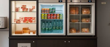 A self-service beverage fridge with multiple shelves containing various drinks and snacks.