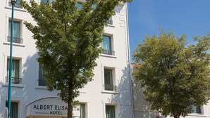 Un hôtel avec une enseigne indiquant « Hôtel Albert Elisa » et un drapeau au sommet.
