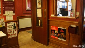 A reception area with a wooden desk, a computer, and various informational posters. - Meridiana (London)