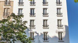 Un bâtiment blanc doté de nombreuses fenêtres et de balcons, avec des devantures de magasins et des enseignes.
