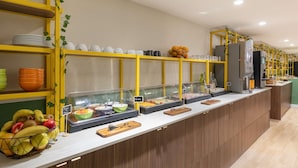 Un espace buffet proposant divers plats, notamment des fruits et des boissons, ainsi qu’une machine à café.