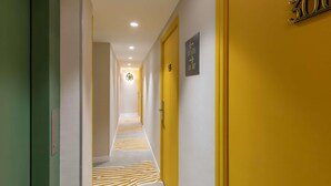 Un couloir d’hôtel avec des portes jaunes, une moquette à motifs zébrés et un panneau indiquant les numéros de chambre 301 et 305.