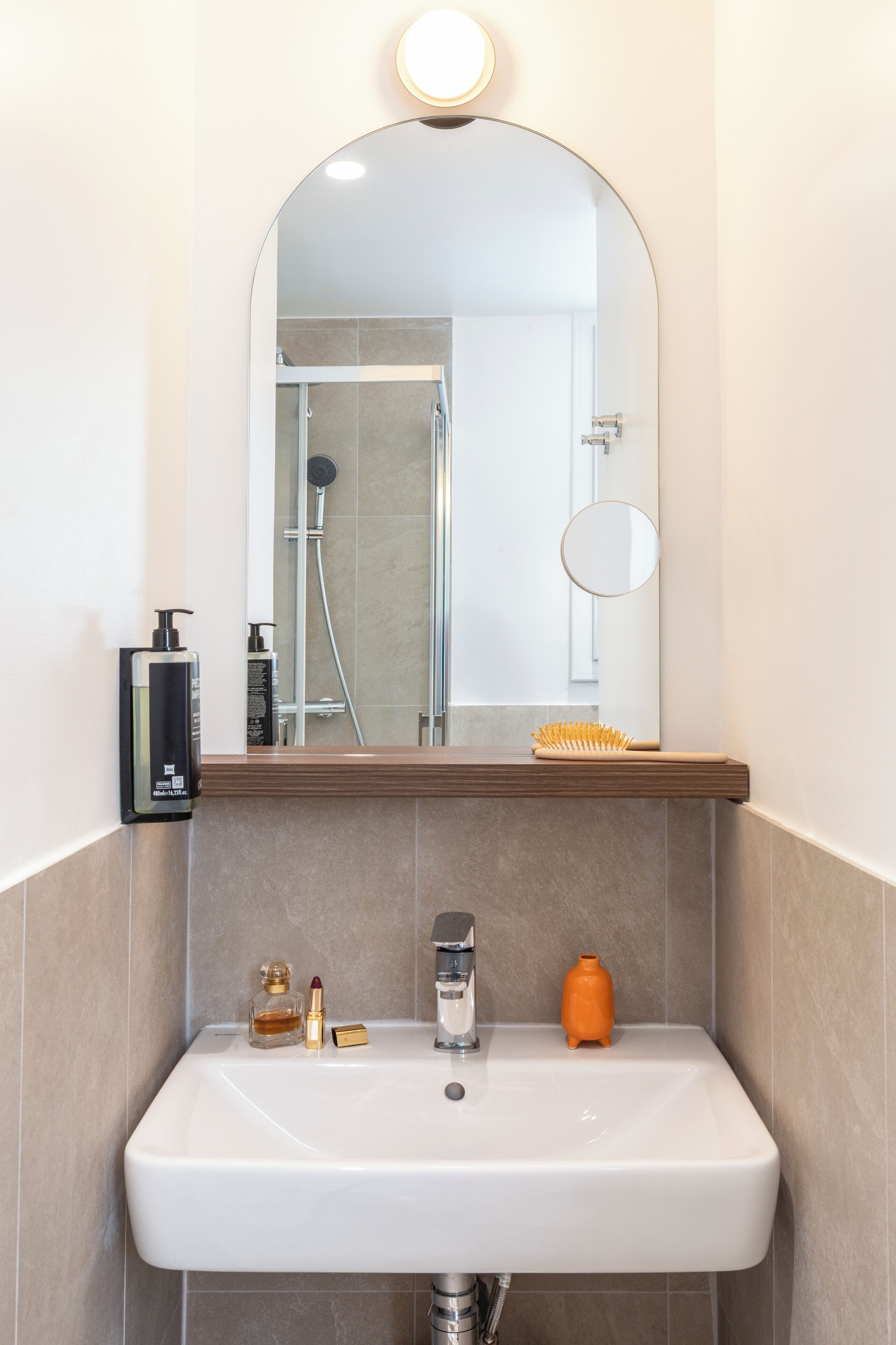 A bathroom with a white sink, a mirror above it, and toiletries on the counter.