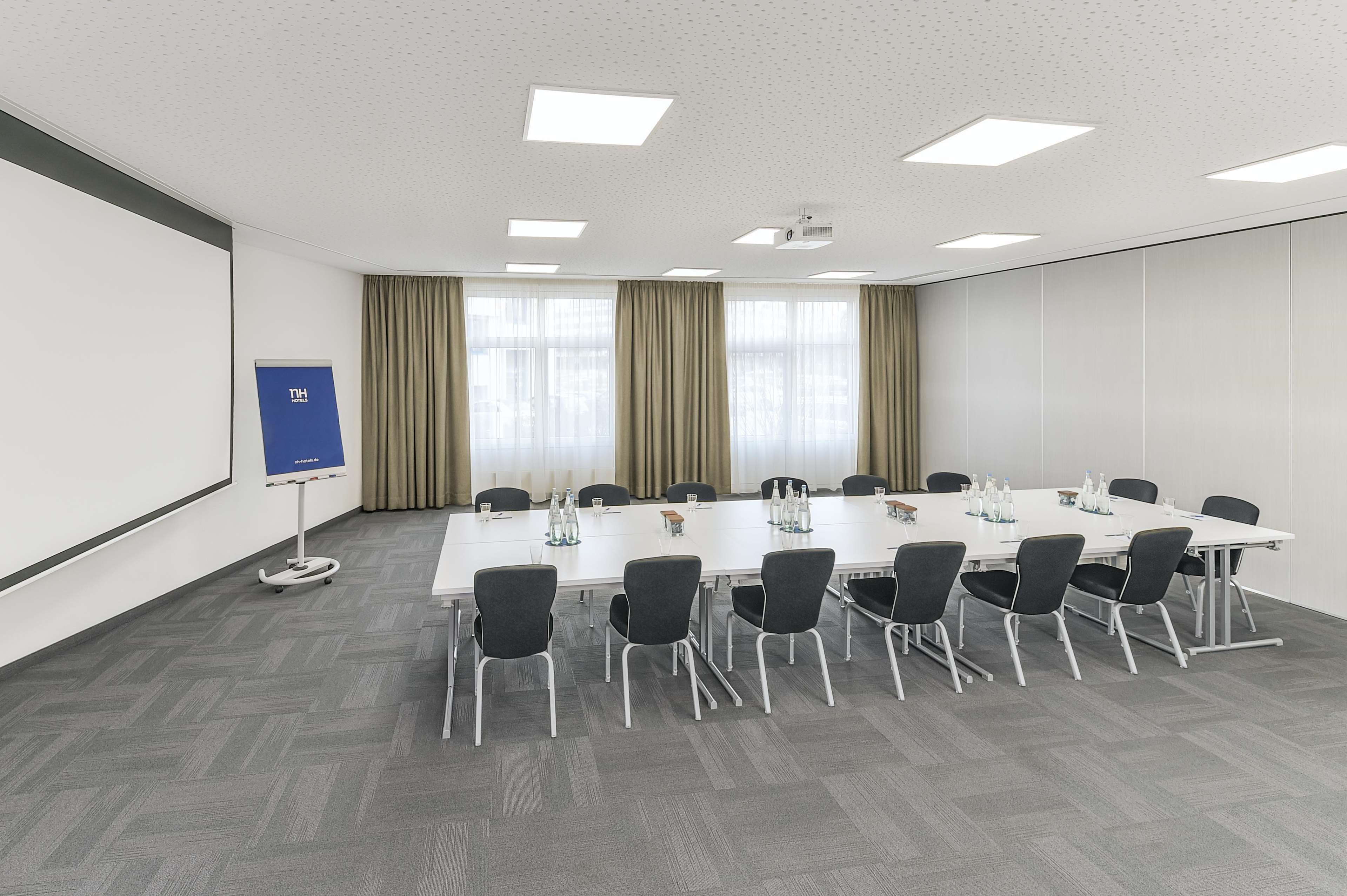 A conference room with a long table, chairs, a projector, and a whiteboard.