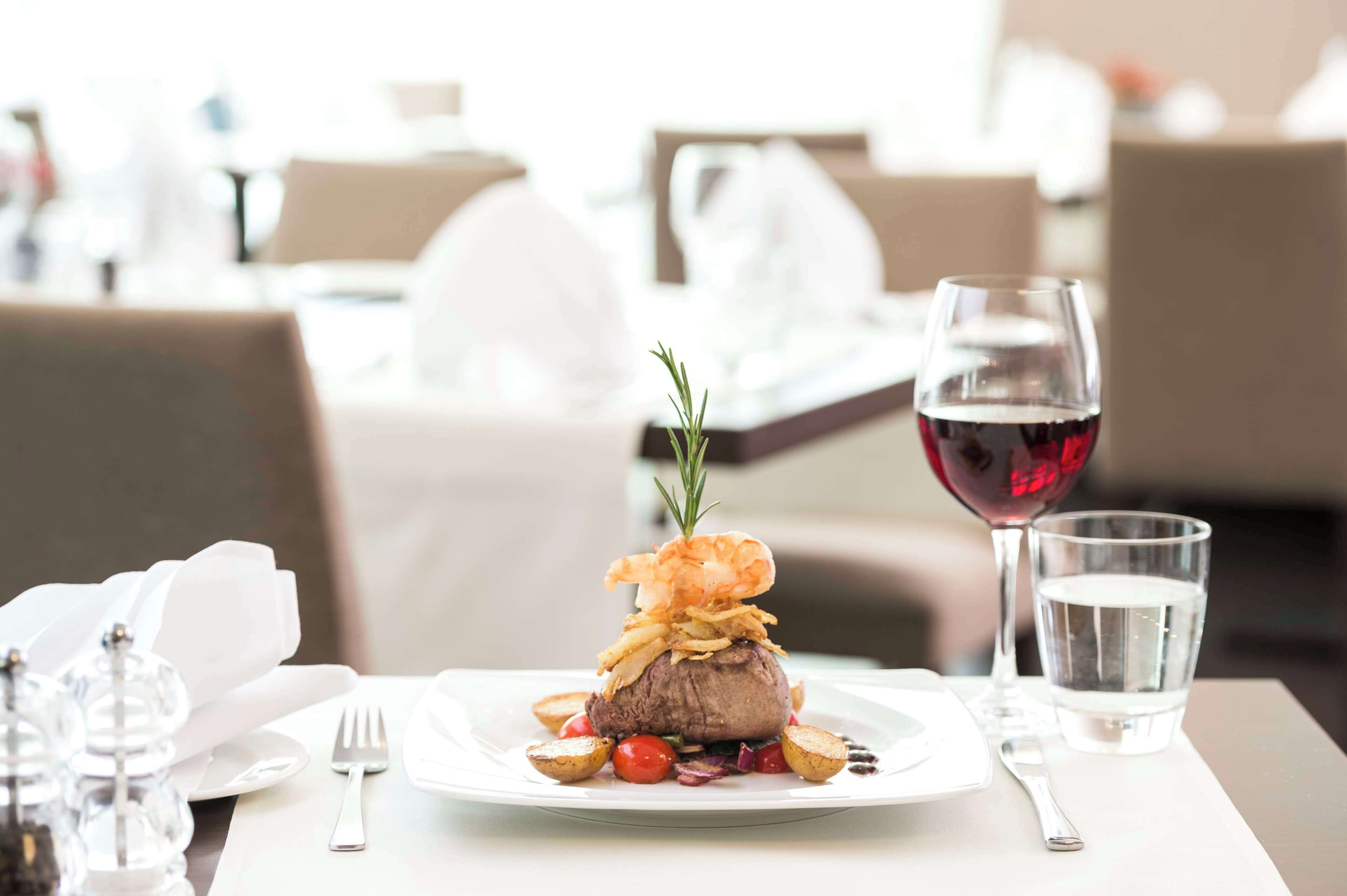 A dining table with a plate of food, a glass of red wine, and a glass of water.