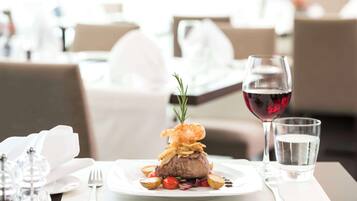 A dining table with a plate of food, a glass of red wine, and a glass of water.