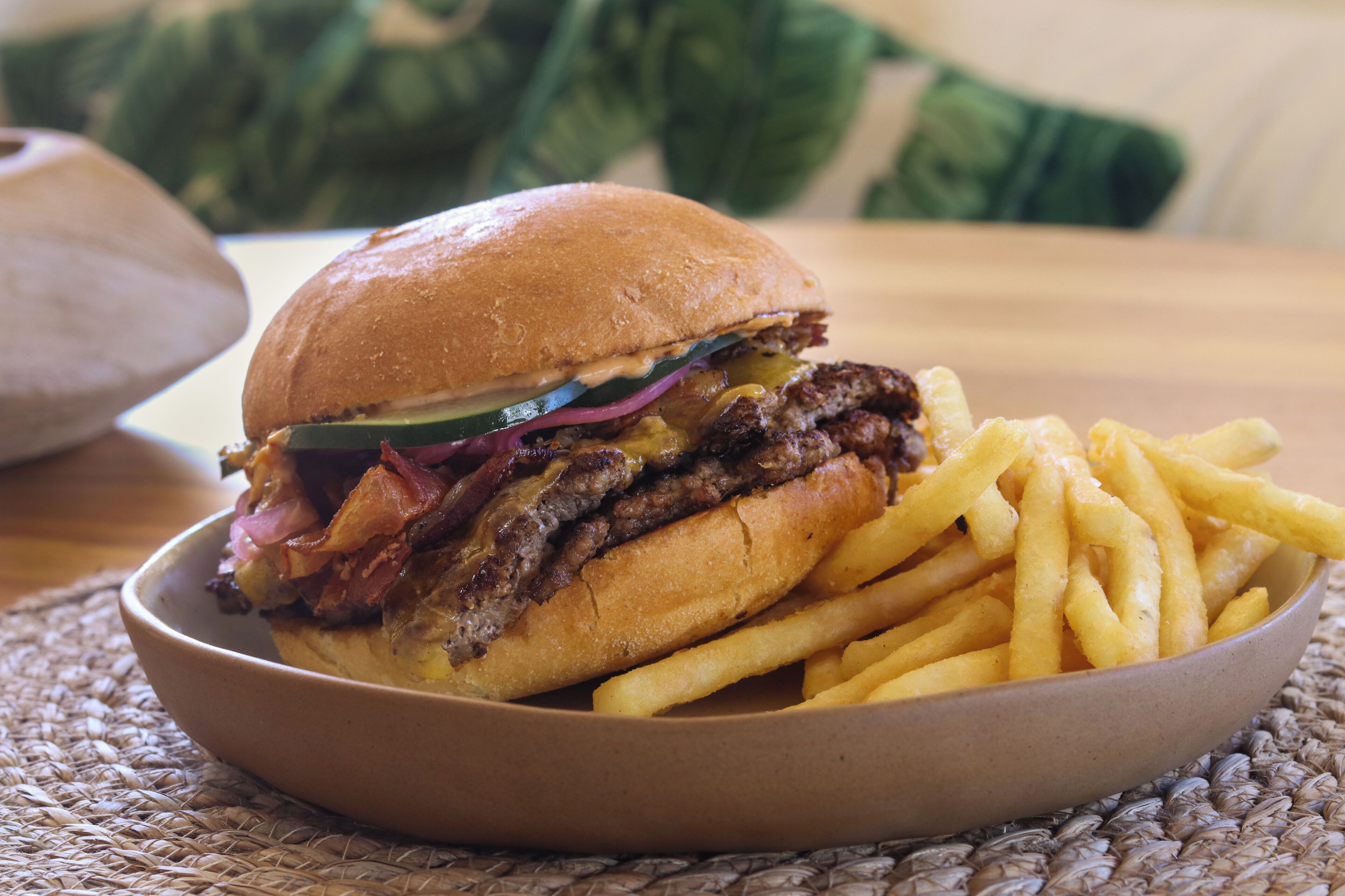 A sandwich with fries on a woven placemat.