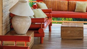 Una terraza de madera con un sofá y una lámpara, rodeada por un paisaje natural.