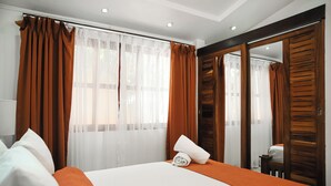 A hotel room with a bed, curtains, and a mirror. - Maravida Social Hotel by Crazy Monkey (Tamarindo)