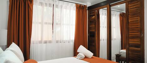 Habitación de hotel con cama, cortinas y espejo.