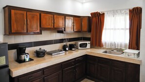 Una cocina con armarios de madera, microondas, cafetera y tostadora.
