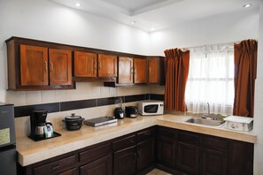 A kitchen with wooden cabinets, a microwave, a coffee maker, and a toaster.