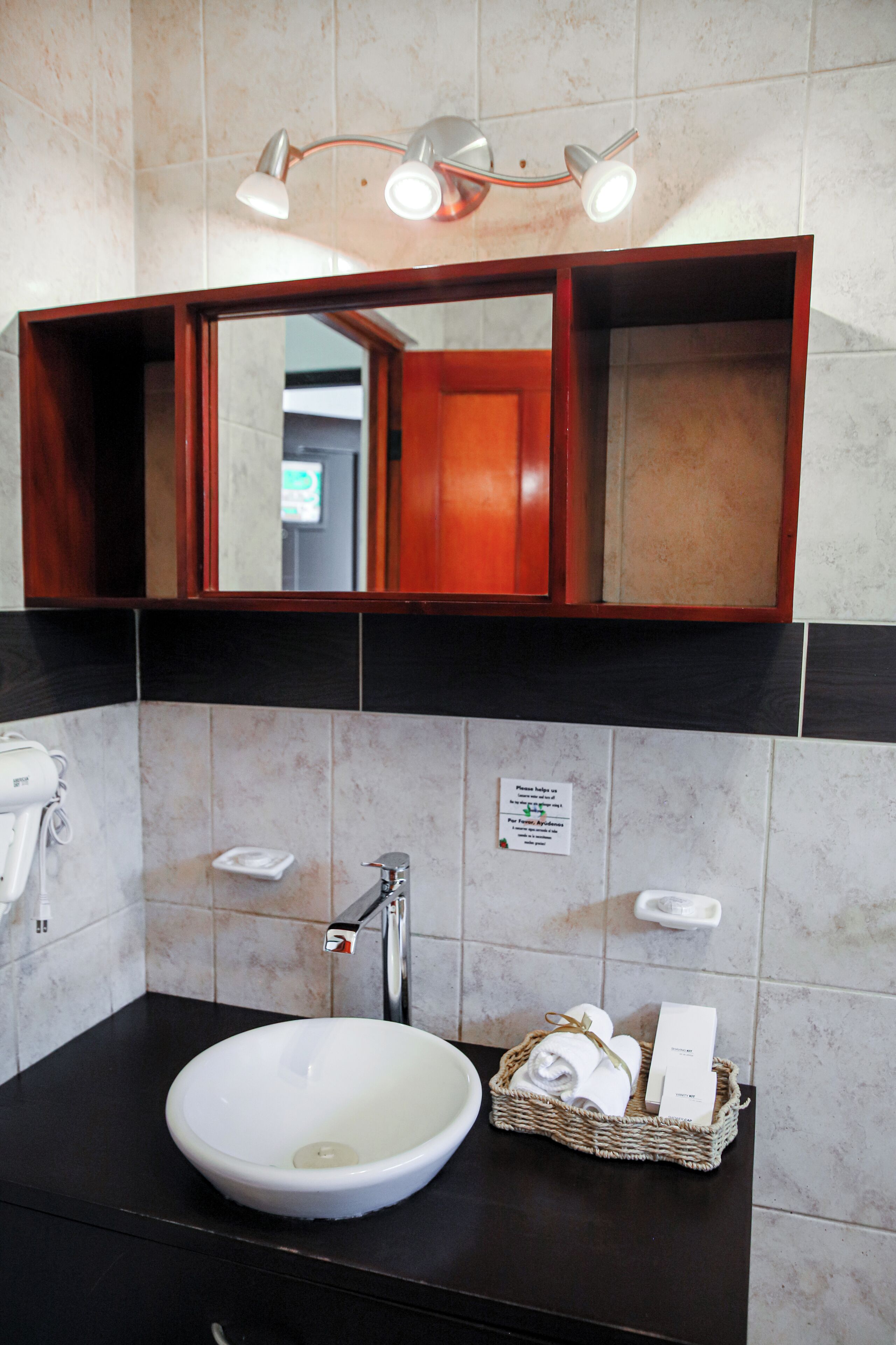A bathroom with a white sink, a mirror, a towel rack, and a basket with toiletries.
