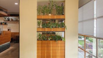 A modern interior with green seating, wooden tables, and a vertical plant wall.