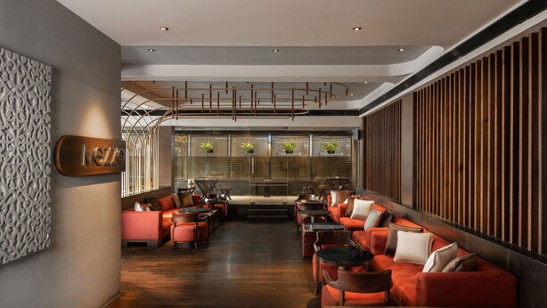 A modern interior with a long seating area, a fireplace, and a decorative wall. - The Avenue Regent (Kanayannur)