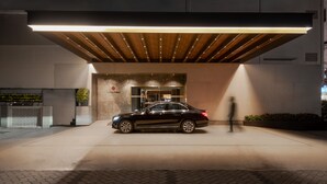 A modern building entrance with a black car parked in front, a wooden ceiling, and a sign that reads "Avenue Elegance." - The Avenue Regent (Kanayannur)