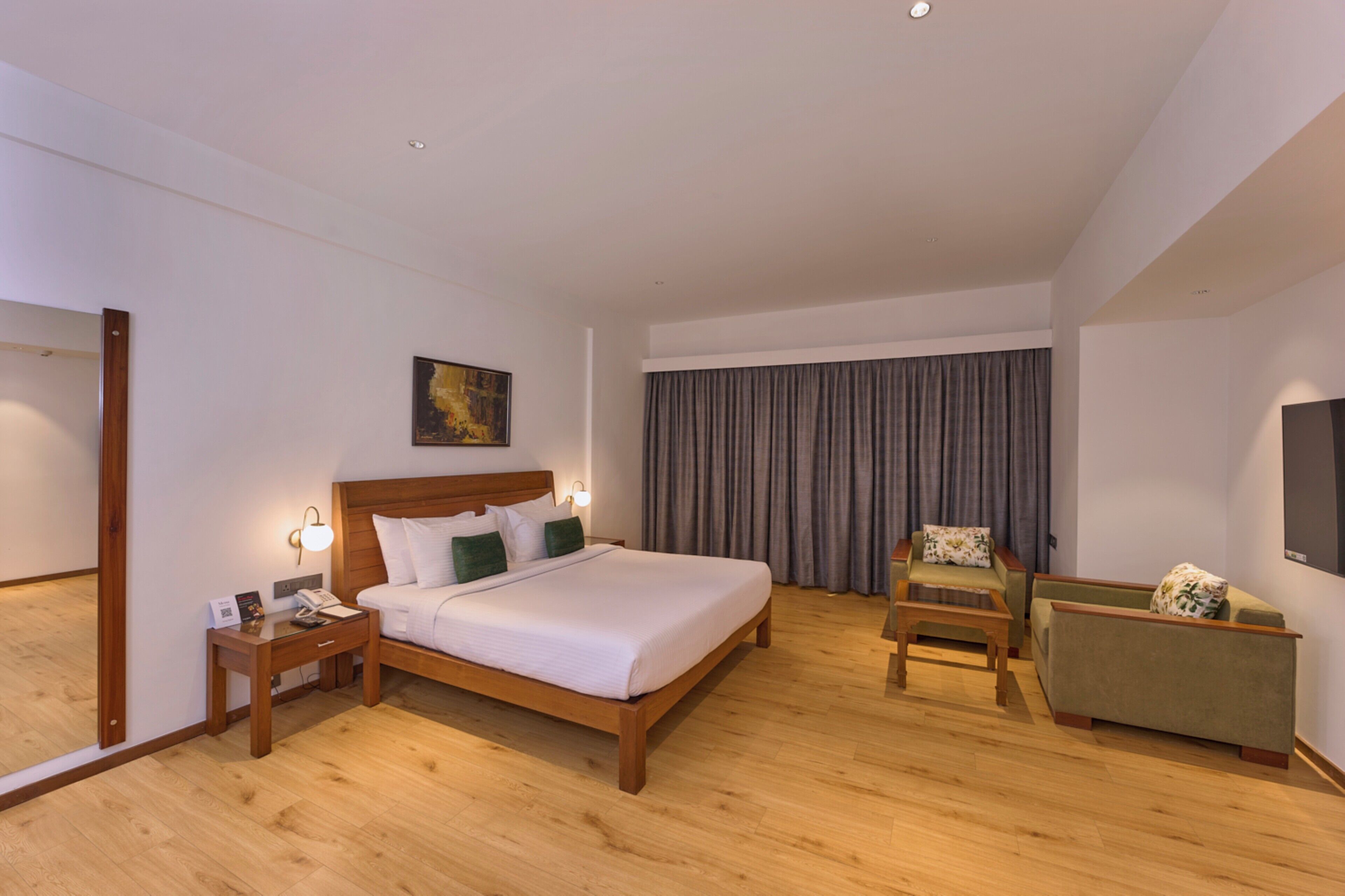 A hotel room with a wooden bed, a nightstand, a chair, a TV, and a large window with curtains.