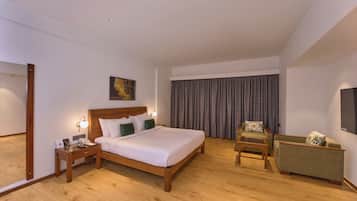 A hotel room with a wooden bed, a nightstand, a chair, a TV, and a large window with curtains.