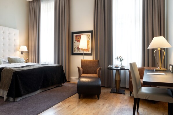 Habitación de hotel con cama, una silla, una mesa y una lámpara.