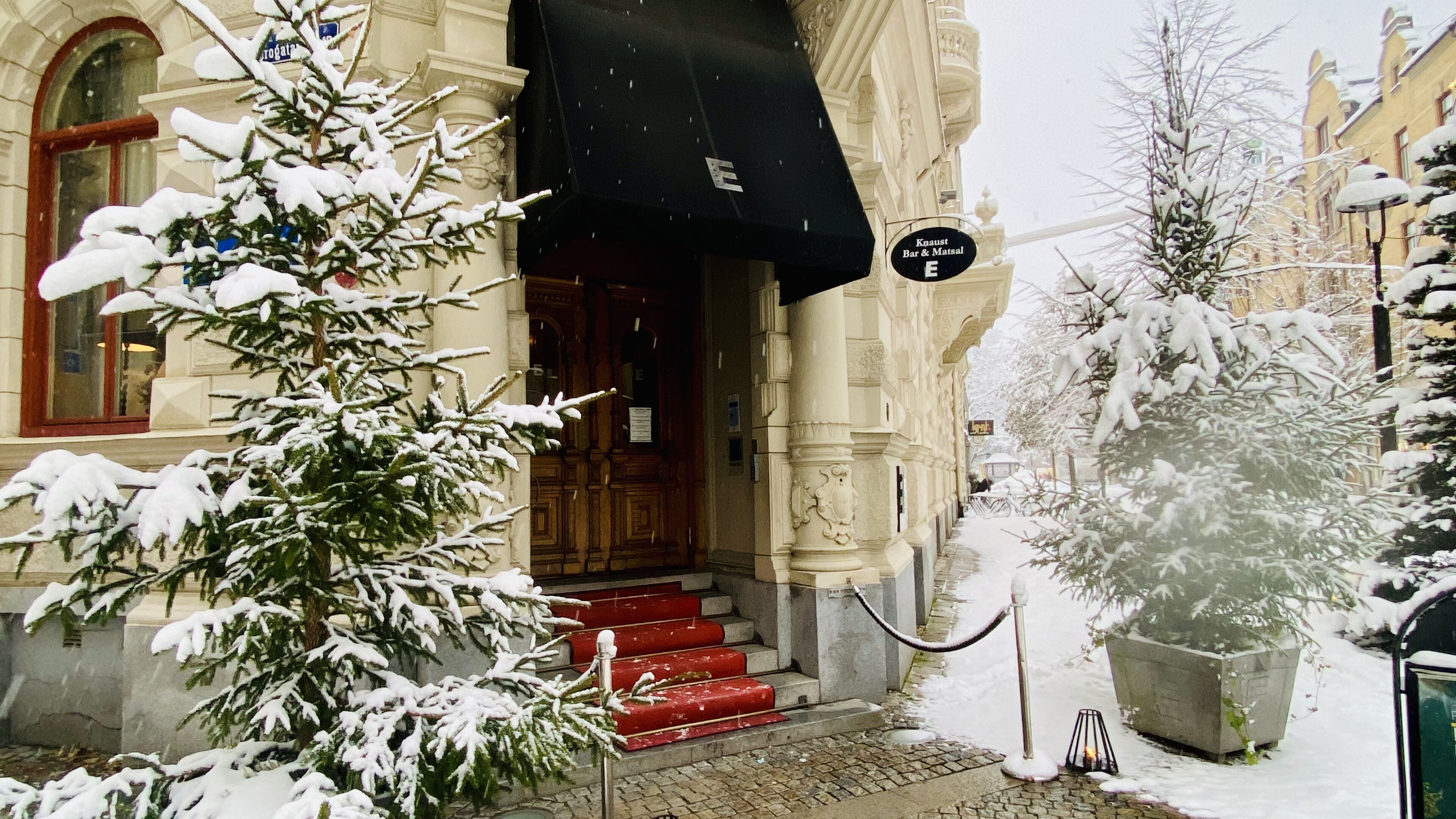 A snow-covered building with a red staircase leading to a wooden door.
