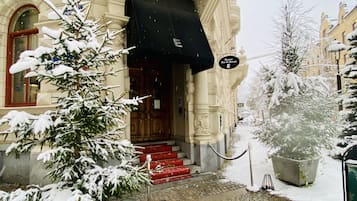 A snow-covered building with a red staircase leading to a wooden door.
