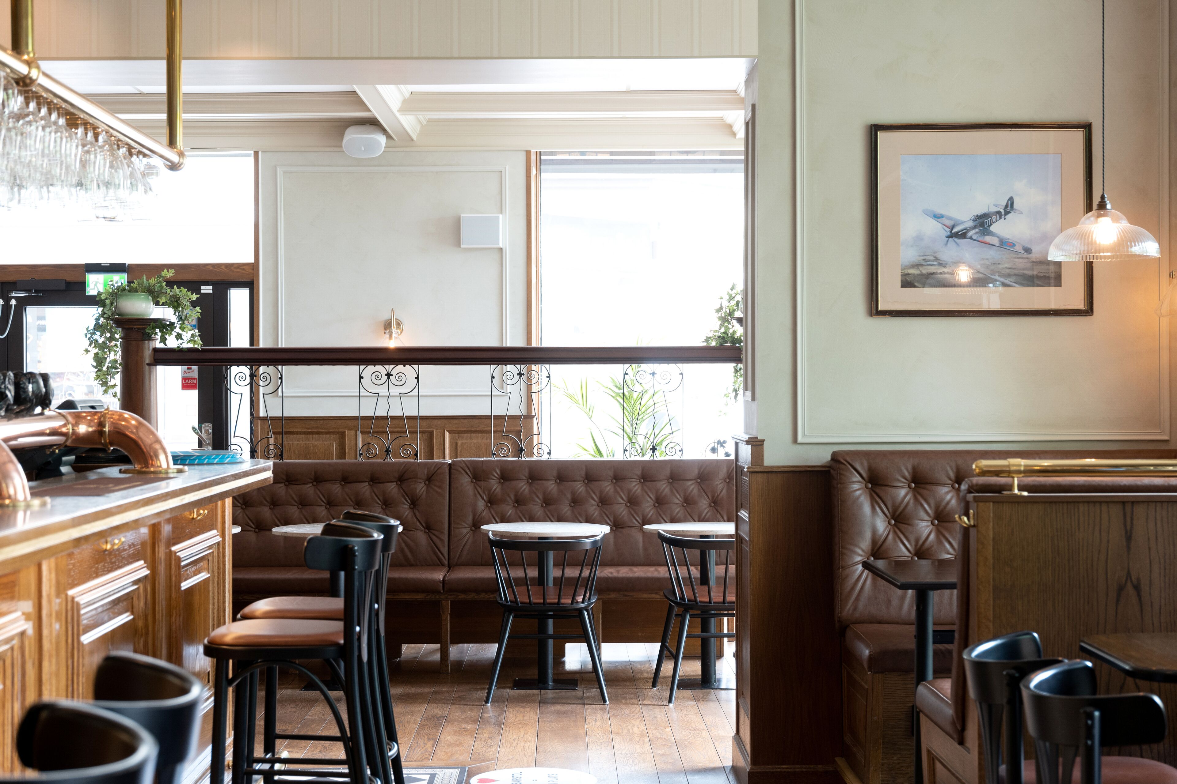 Un restaurante con zona de bar, disposición de mesas y un cuadro en la pared.