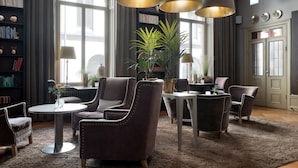 Ein modernes Wohnzimmer mit Ledersesseln, einem runden Couchtisch und einem Bücherregal voller Bücher.