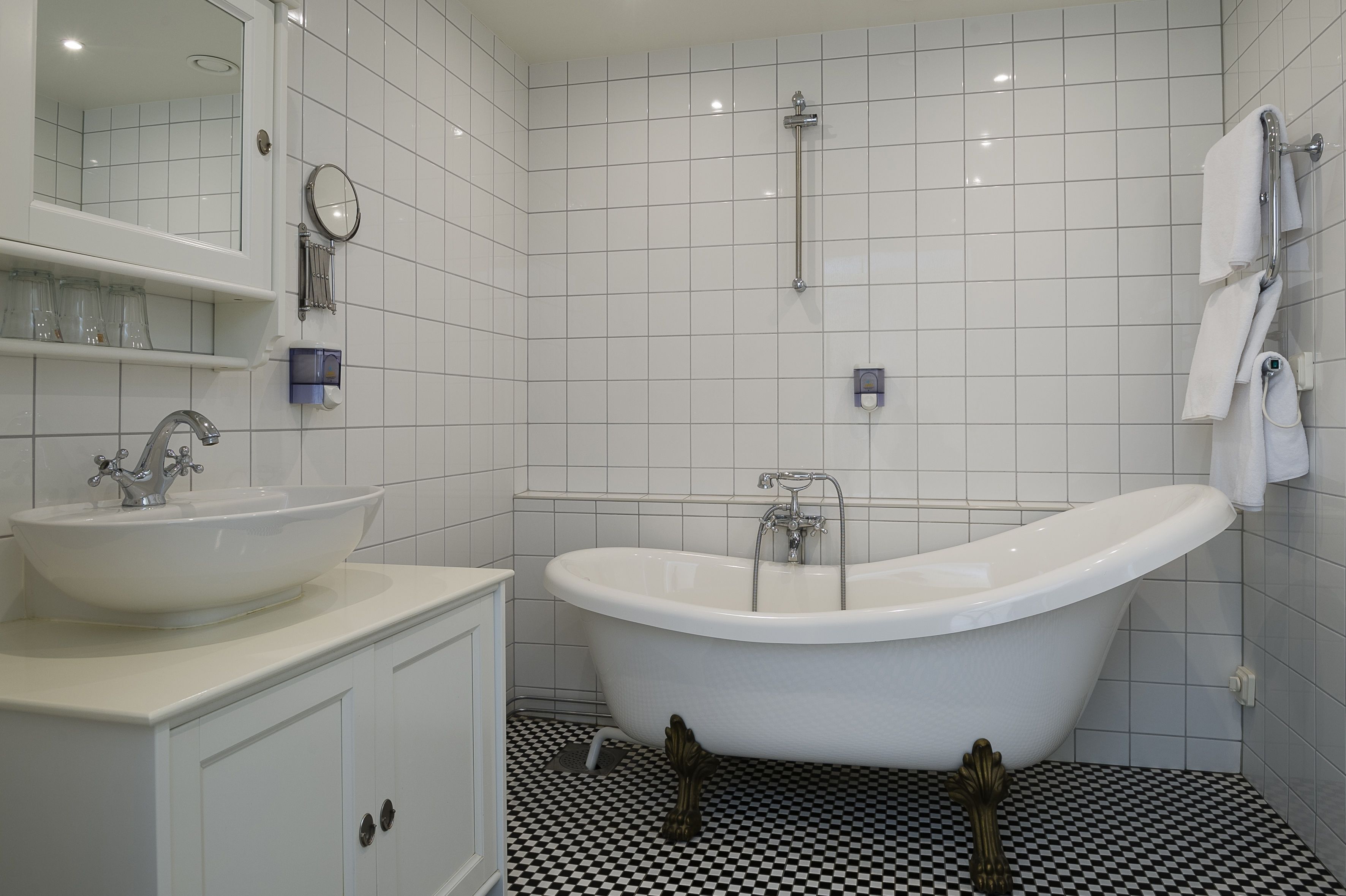 A bathroom with a white sink, vanity, and a freestanding bathtub.