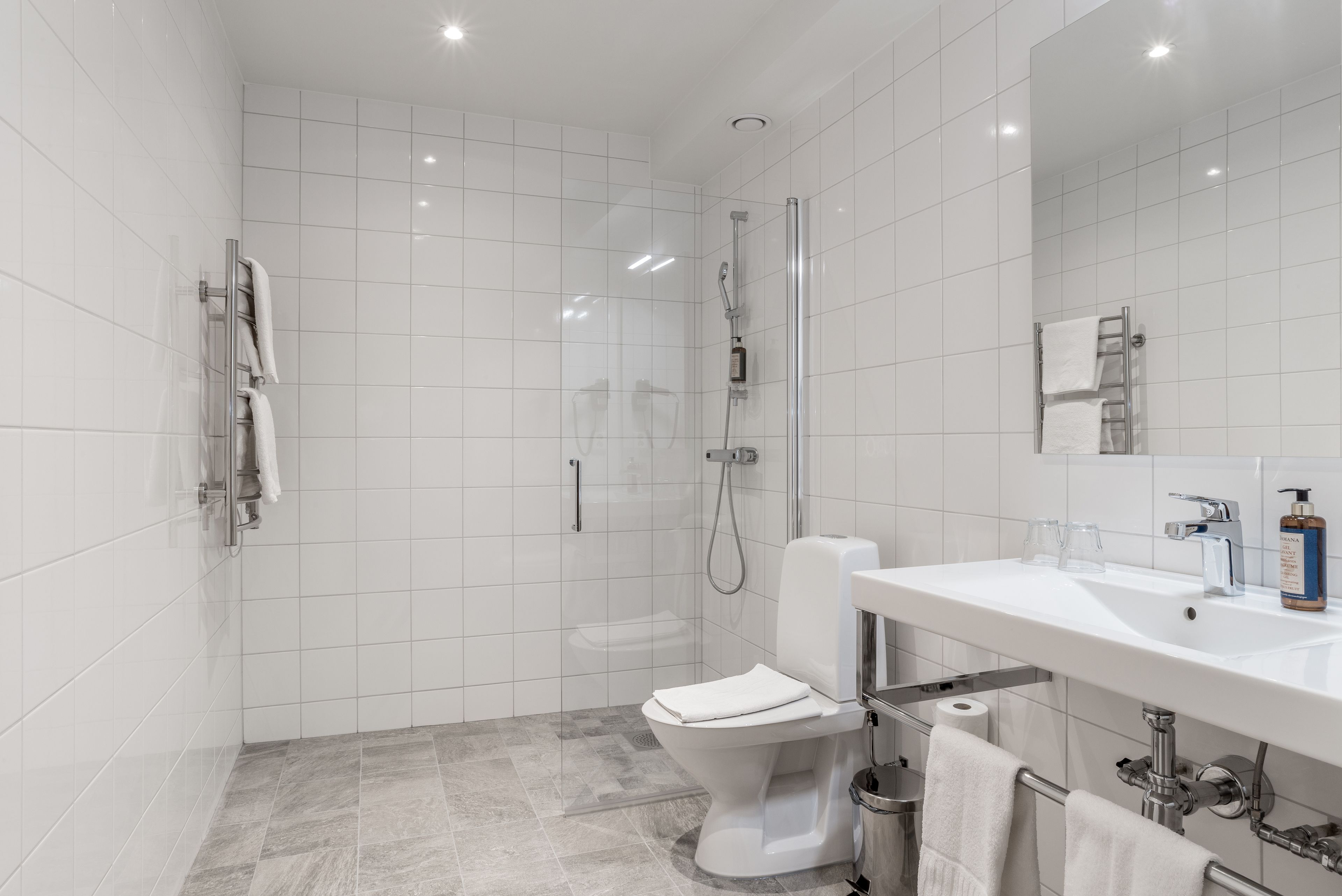 A modern bathroom with a shower, toilet, and sink.