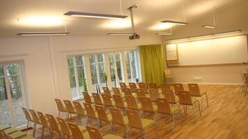 A conference room with rows of chairs, large windows, and a projector screen.