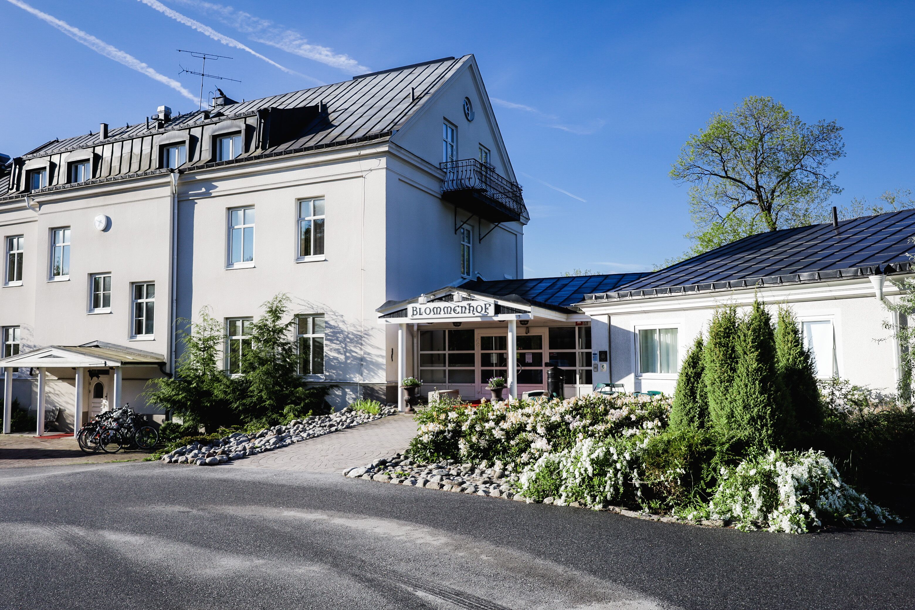 Un hotel con fachada blanca, un vestíbulo cubierto y un balcón.