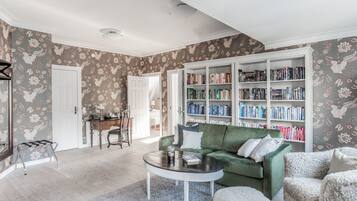 Una sala de estar con un sofá verde, una mesa de centro y una estantería llena de libros.