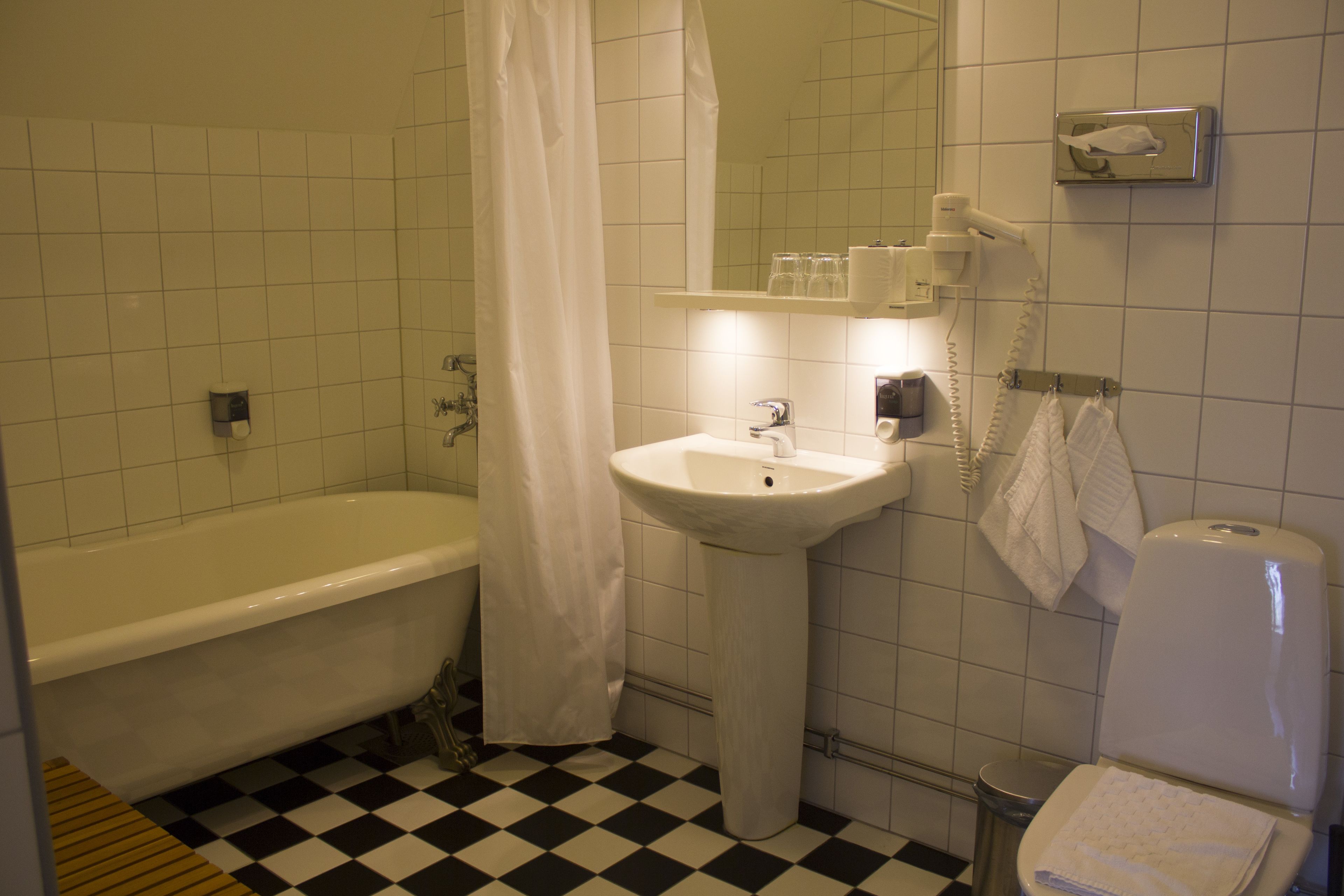 A bathroom with a bathtub, sink, toilet, and a shower curtain.