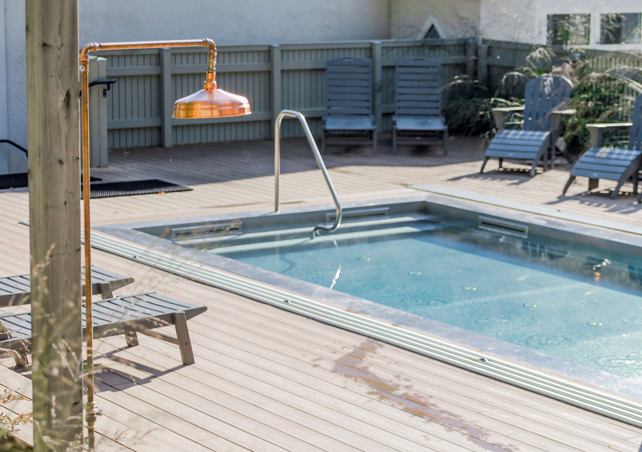 Una piscina rectangular con una terraza de madera alrededor.