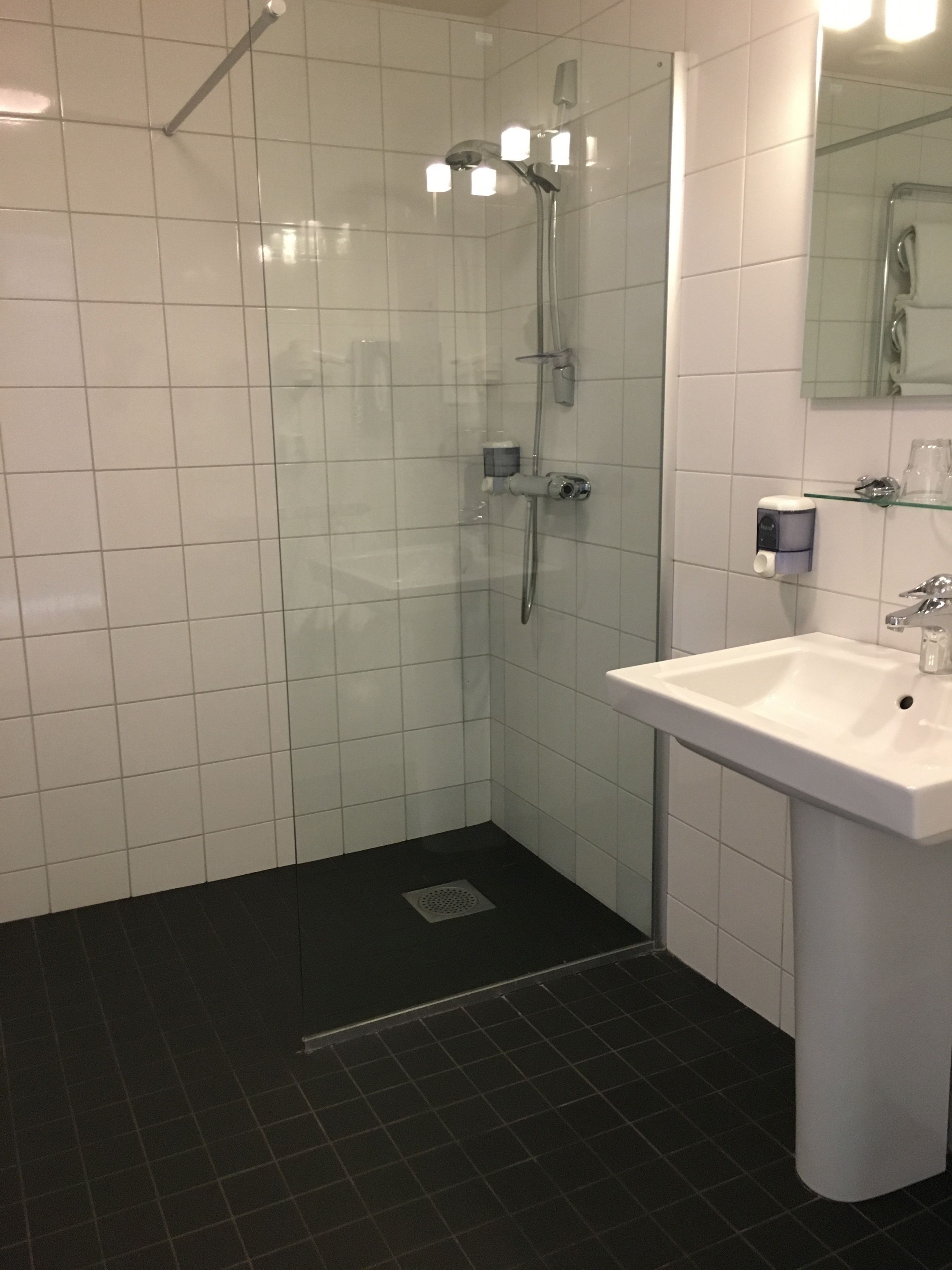 A modern bathroom with a glass-enclosed shower, a white sink, and a mirror above it.