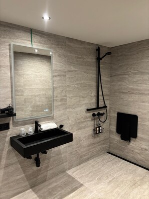 A modern bathroom with a rectangular sink, a handheld showerhead, a towel rack, and a mirror. - Cortina Hotel (Wevelgem)
