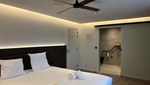 A modern hotel room with a large bed, a ceiling fan, and a view of a hallway. - Cortina Hotel (Wevelgem)