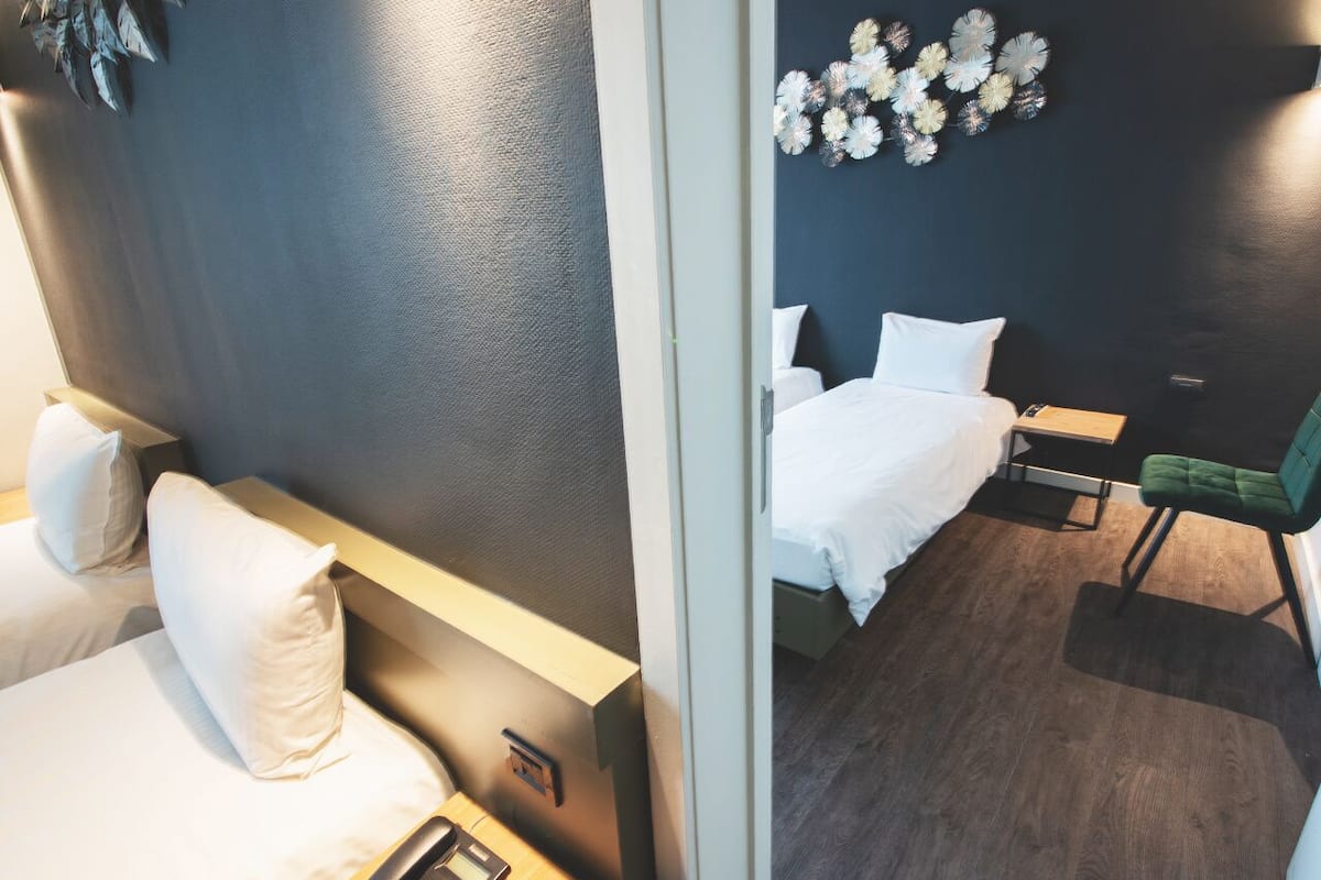 A hotel room with two beds, a desk, and a chair.