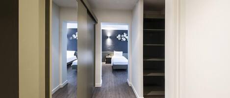 Una habitación de hotel moderna con cama, mesita de noche y velador. Se ve una escalera que sube a un piso superior.